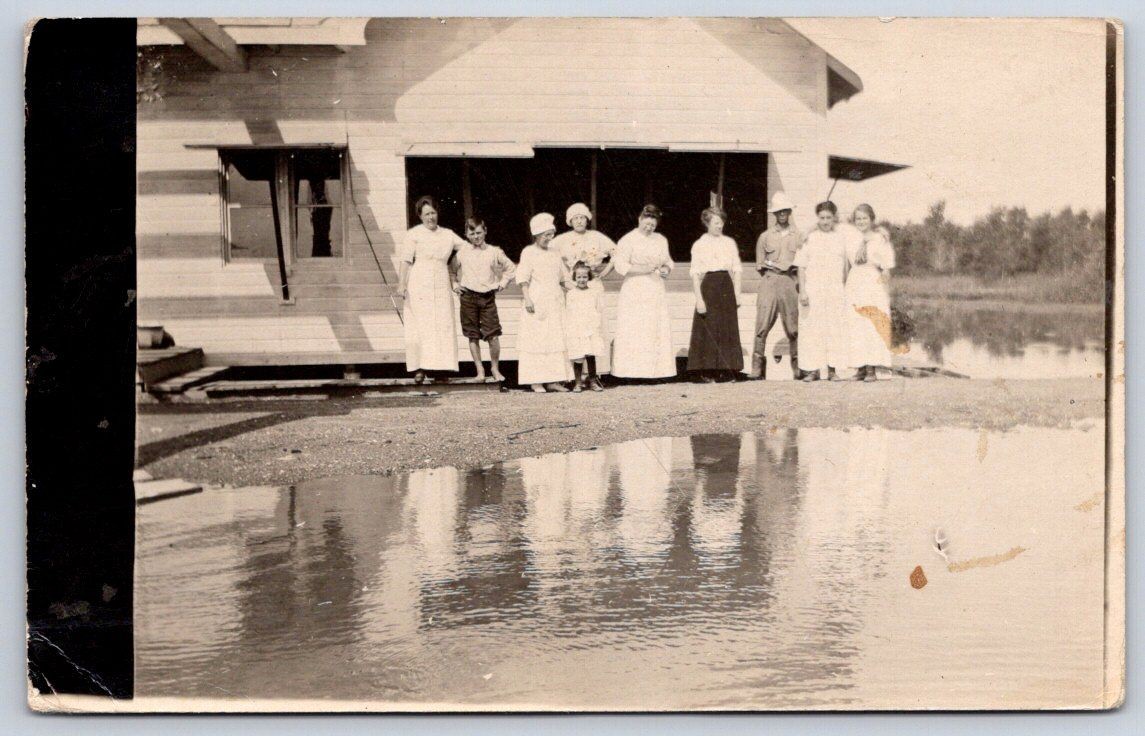 Vintage women men children group photo by lake house 1900s Rppc